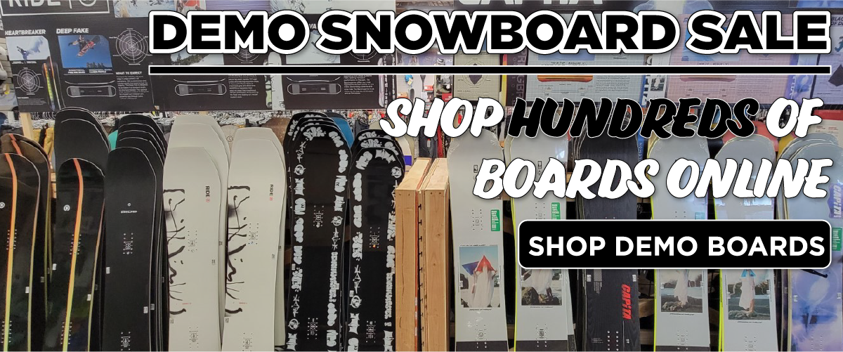 demo_boards_1200x500 A row of various snowboards is displayed upright in a shop with large text reading, “Demo Snowboard Sale,” “Shop Hundreds of Boards Online,” and a button labeled “Shop Demo Boards.”.
