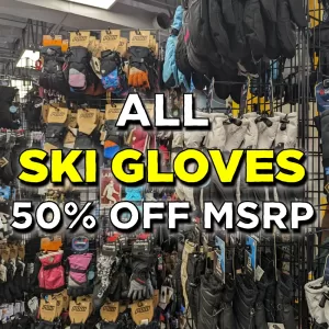 Display of various ski gloves on racks in a store, with a large sign overlaid that reads, ALL SKI GLOVES 50% OFF MSRP in bold white and yellow text.